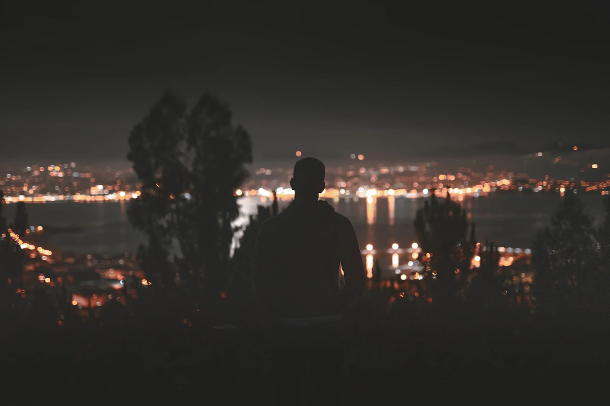 Two men sitting together looking out over city lights at night