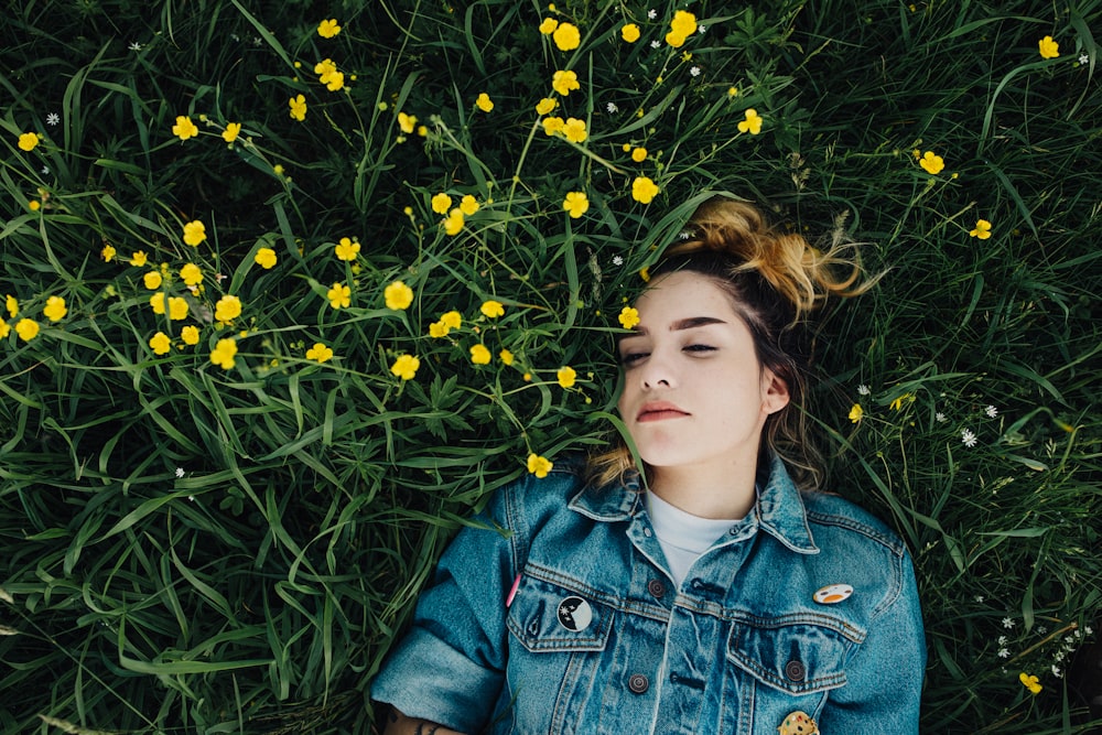 woman in blue chambray jacket lying on green grass