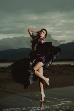 woman wearing purple dress standing on shoreline