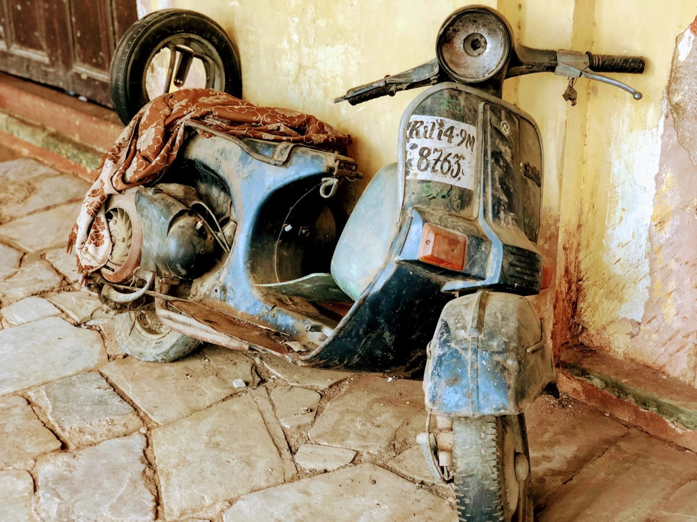 scooter do motor preto apoiando-se na parede durante o dia