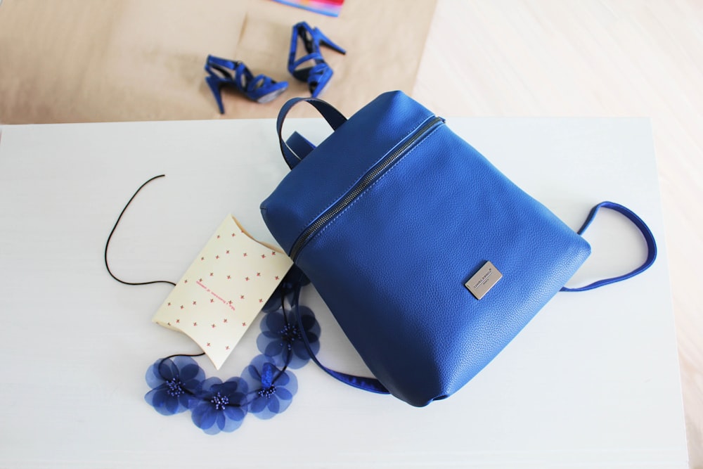 blue leather backpack placed on white wooden table