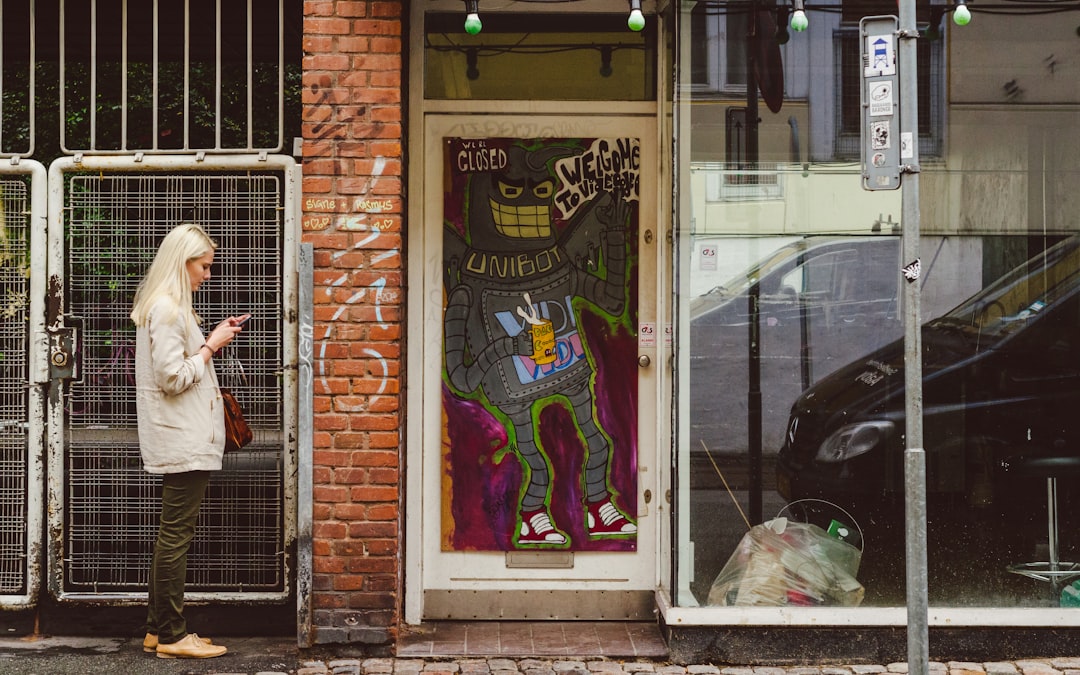 woman standing beside building holding smartphone, I swear this girl stood still just to be in my photo. i was originall