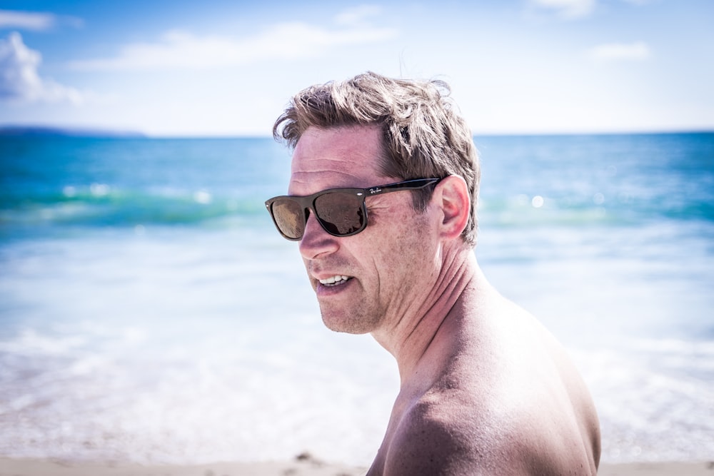 man wearing black-framed Wayfarer-style sunglasses standing near the body of water