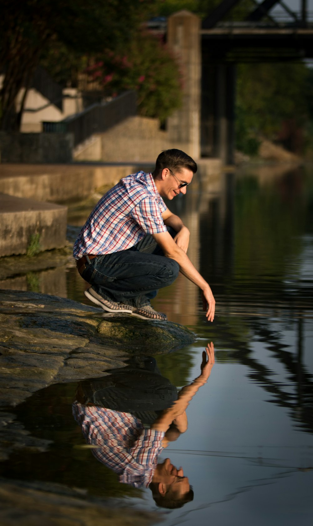 man sitting on rock near body of water