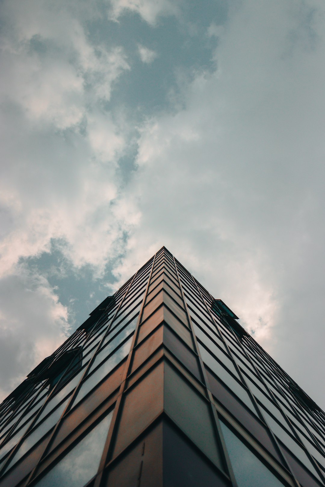 low-angle photography of glass building under thick clouds