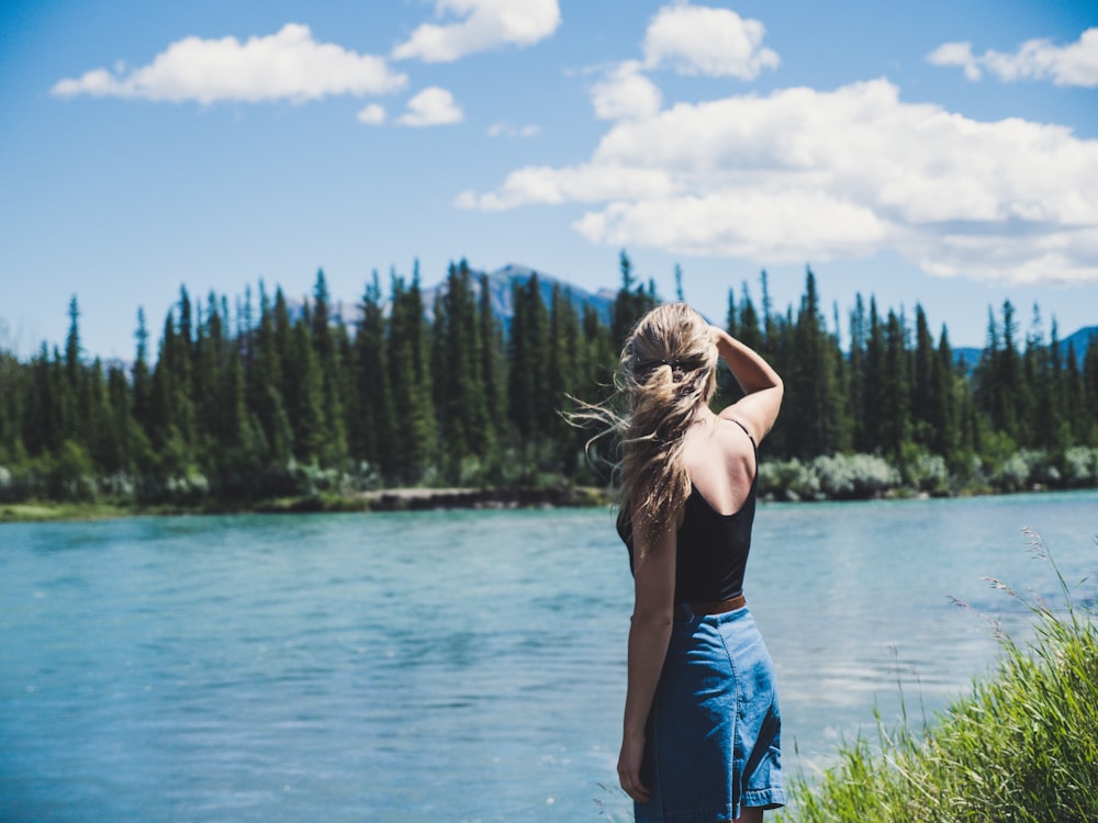 woman in black camisole standing near river