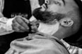 grayscale photo of man shaving his beard