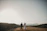 a bride and groom walking on a hill
