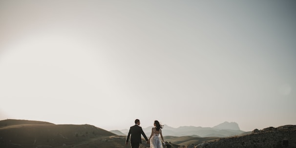 a bride and groom walking on a hill