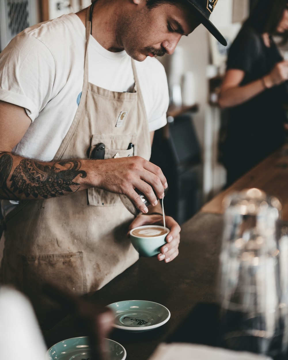 man pouring latte on coffee