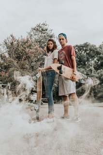 man and woman carrying wooden longboards on road