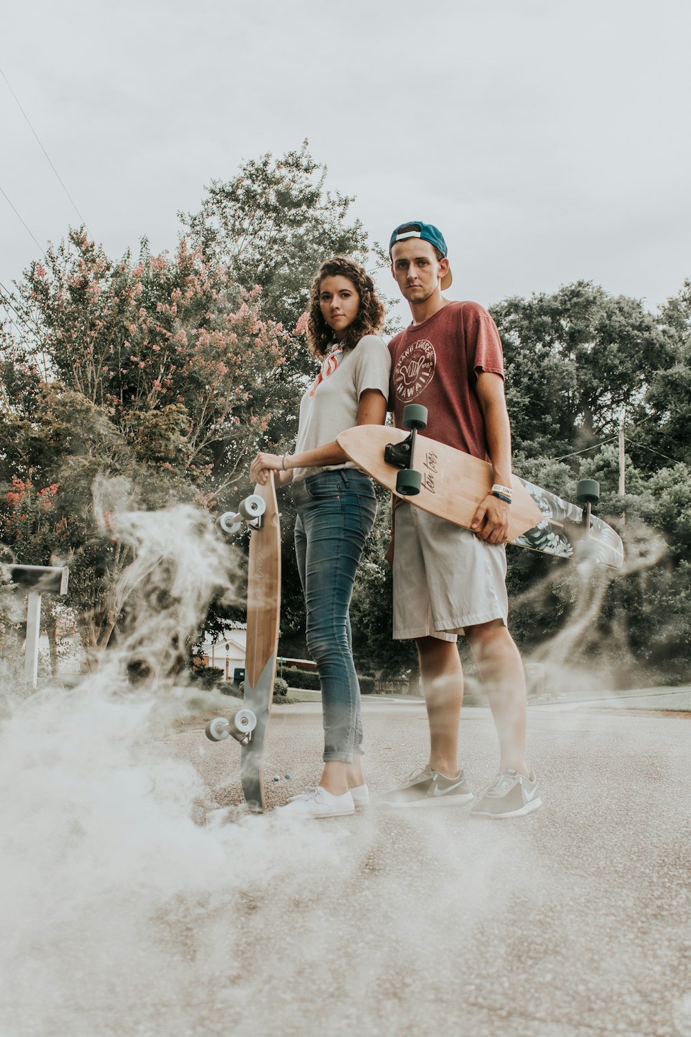 Homem e mulher carregando longboards de madeira na estrada