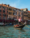 people riding boat beside buildings