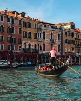 people riding boat beside buildings