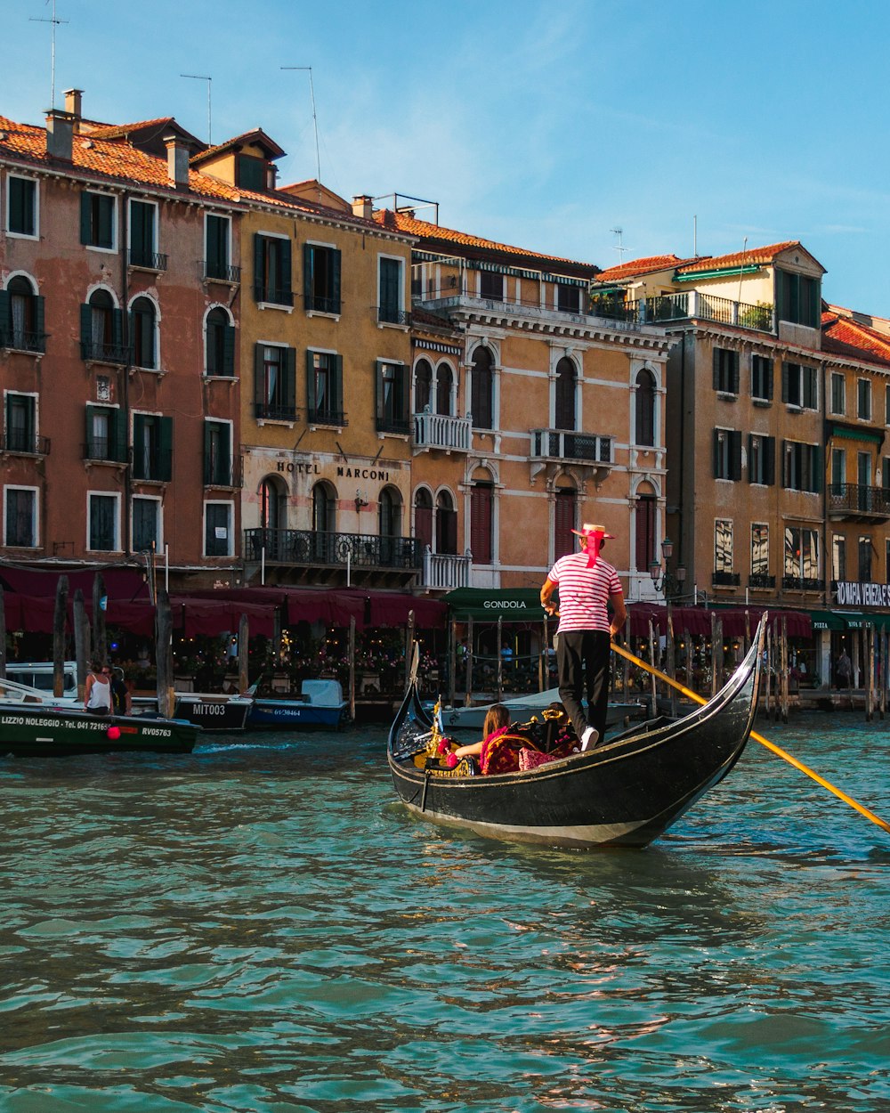 people riding boat beside buildings