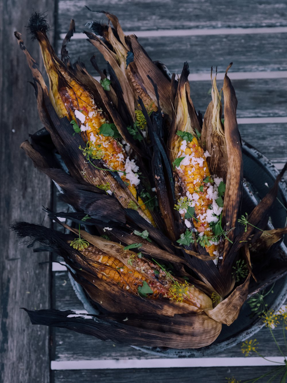 four grilled corns on gray bucket