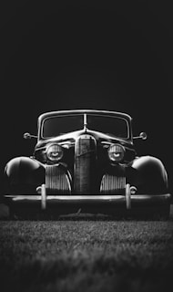 greyscale photo of classic vehicle on ground