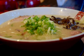 Close-up of a vibrant bowl of ramen with fresh herbs and golden broth.