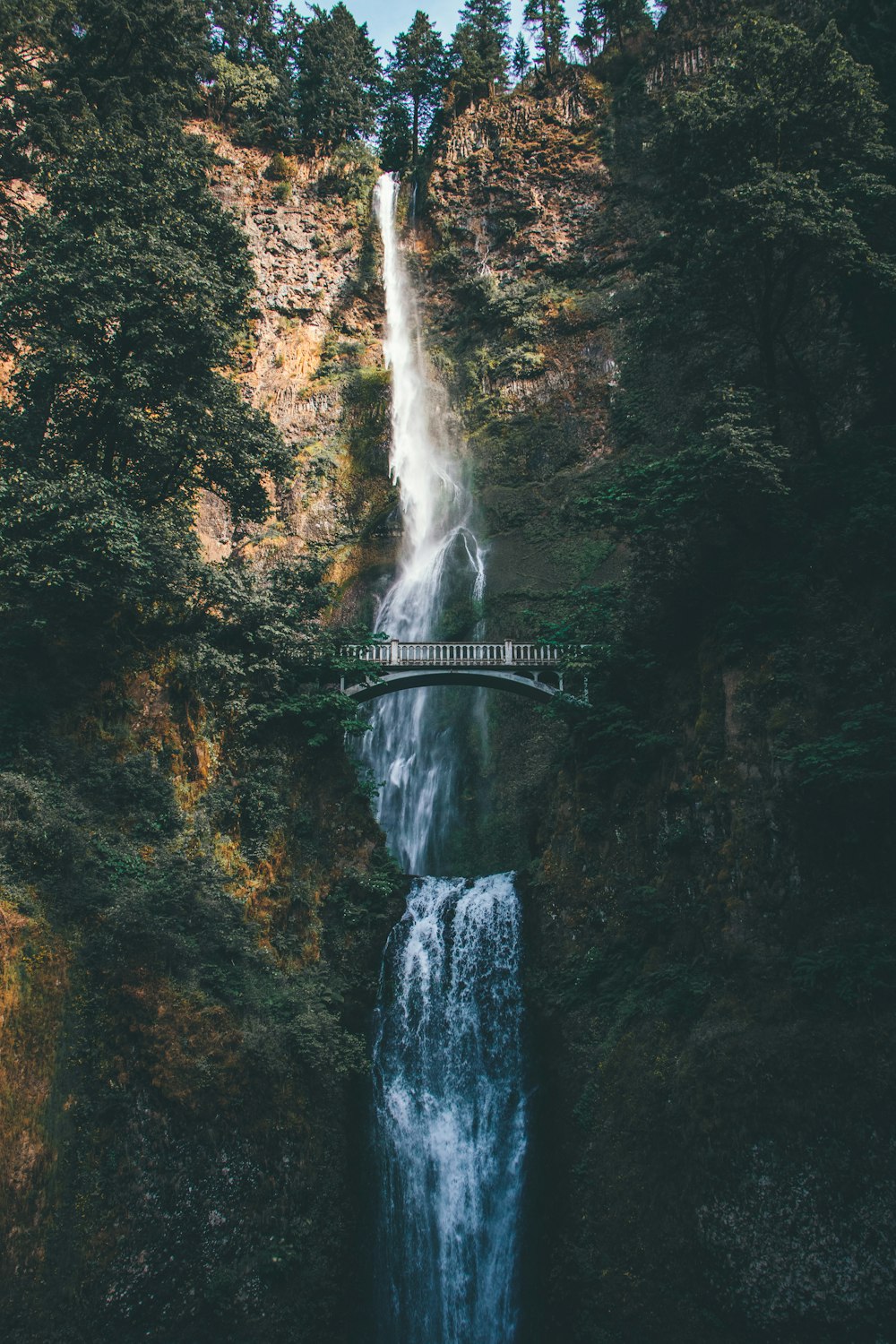 bridge overlooking waterfalls at daytime