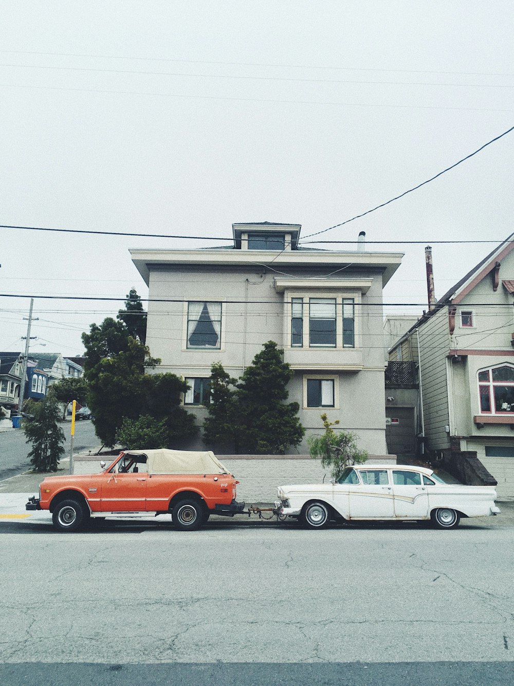 red pickup truck and white sedan parked near house at daytime