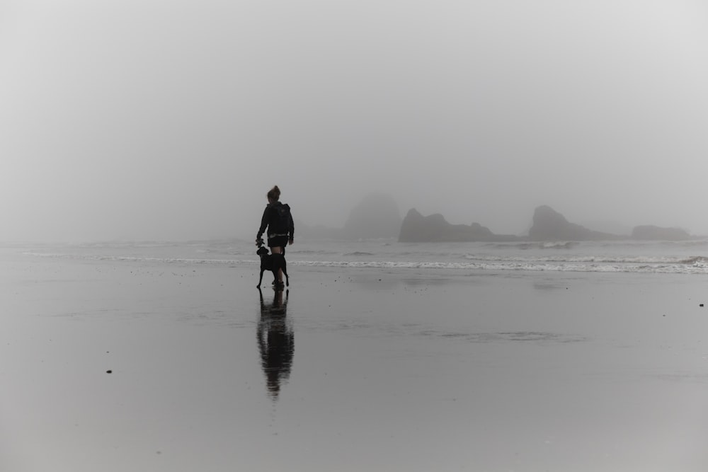 homem caminhando na costa ao lado do cão