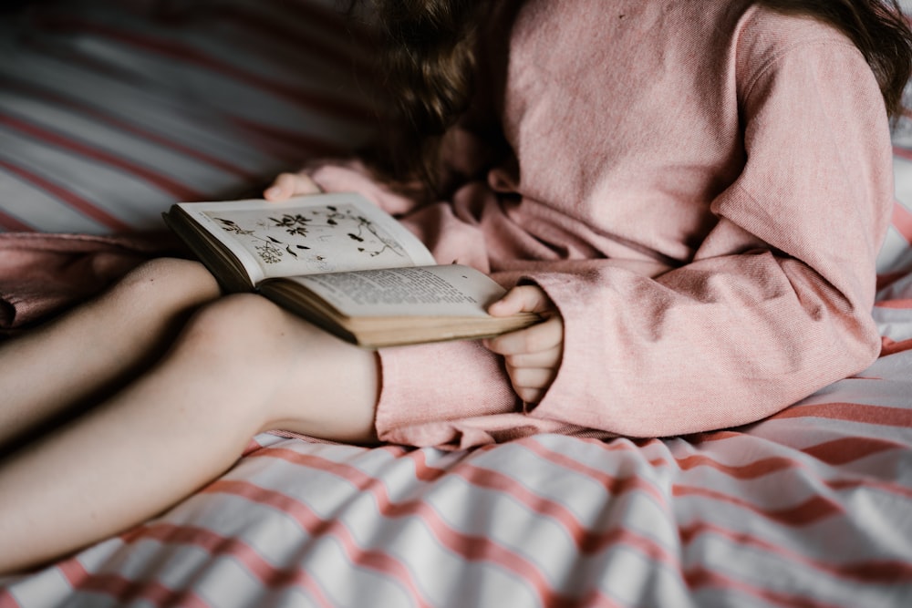 woman reading book on white and red textile