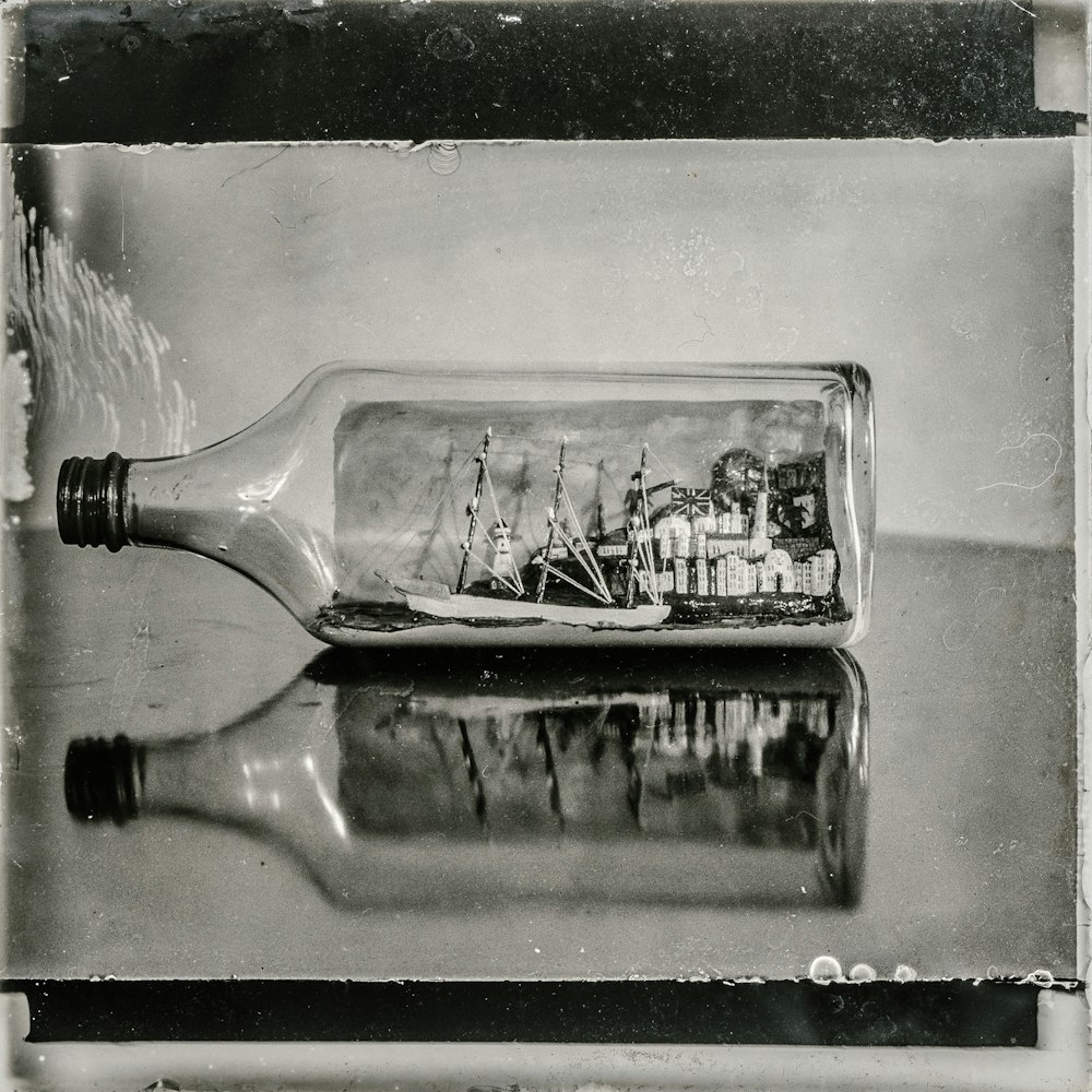 grayscale photo of boat in bottle table decoration