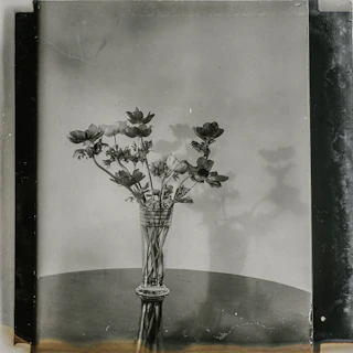 Artistic shot of a decorative vase filled with vibrant flowers on a wooden table.