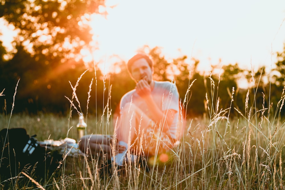 man sitting on green grass eating food during sunrise