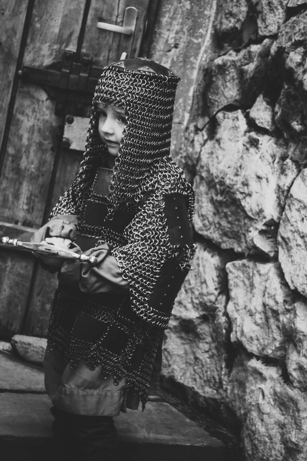 grayscale photo of child wearing chain mail