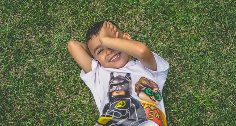 boy laying on green grass