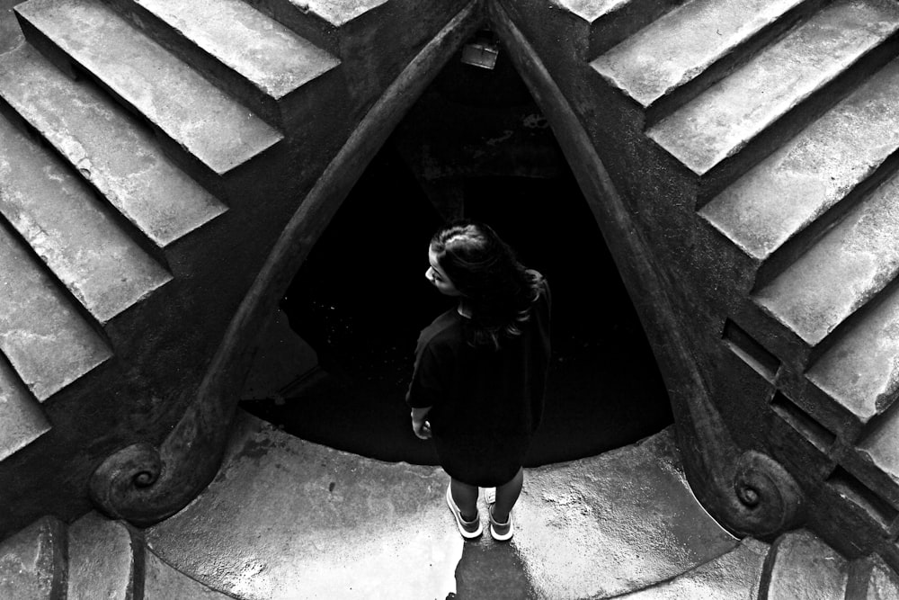grayscale photo of woman standing near stairs
