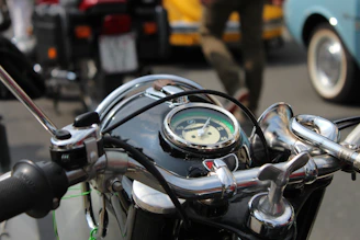 Dark-themed close-up of a vintage motorcycle handlebar with a blurred rock concert crowd in the background