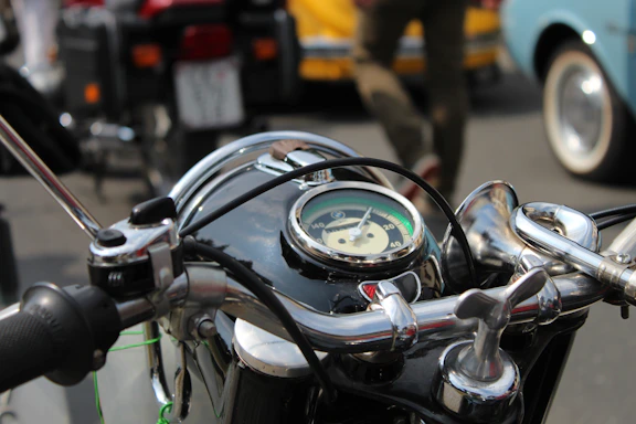 Dark-themed close-up of a vintage motorcycle handlebar with a blurred rock concert crowd in the background