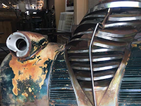 Close-up of a rat rod’s rusty exterior with detailed metalwork and custom decals under soft lighting.