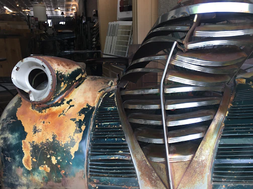 A close-up shot of a weathered vintage car hood with rust patterns blending into the dark background.