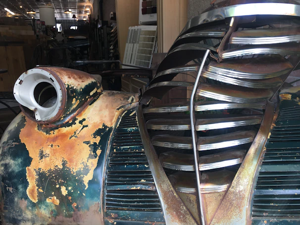 Close-up of a rat rod’s rusty exterior with detailed metalwork and custom decals under soft lighting.