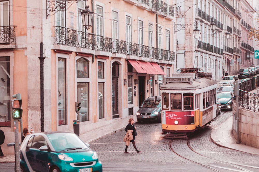 woman wearing black coat passing on road while tram is near during daytime