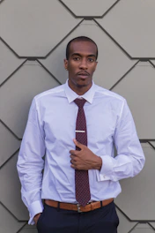 Man wearing a pastel-colored plain shirt, buttoned up neatly in a modern office setting.