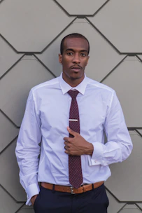 Man wearing a pastel-colored plain shirt, buttoned up neatly in a modern office setting.