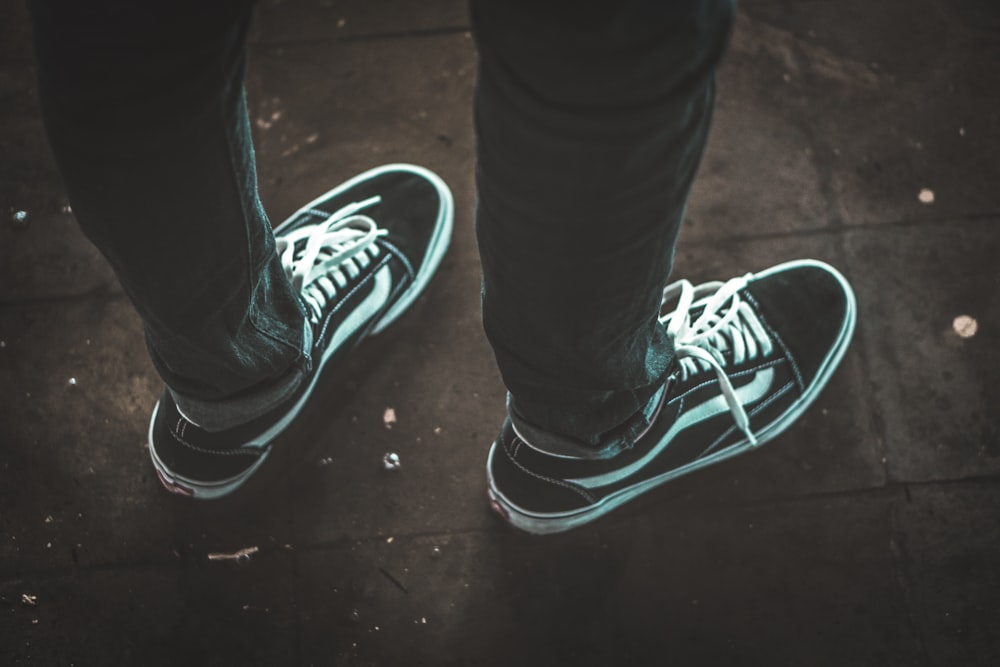 person wearing black-and-white Vans Old-Skool senakers