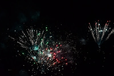 Close-up of colorful firecrackers bursting against a dark night sky with golden sparks.