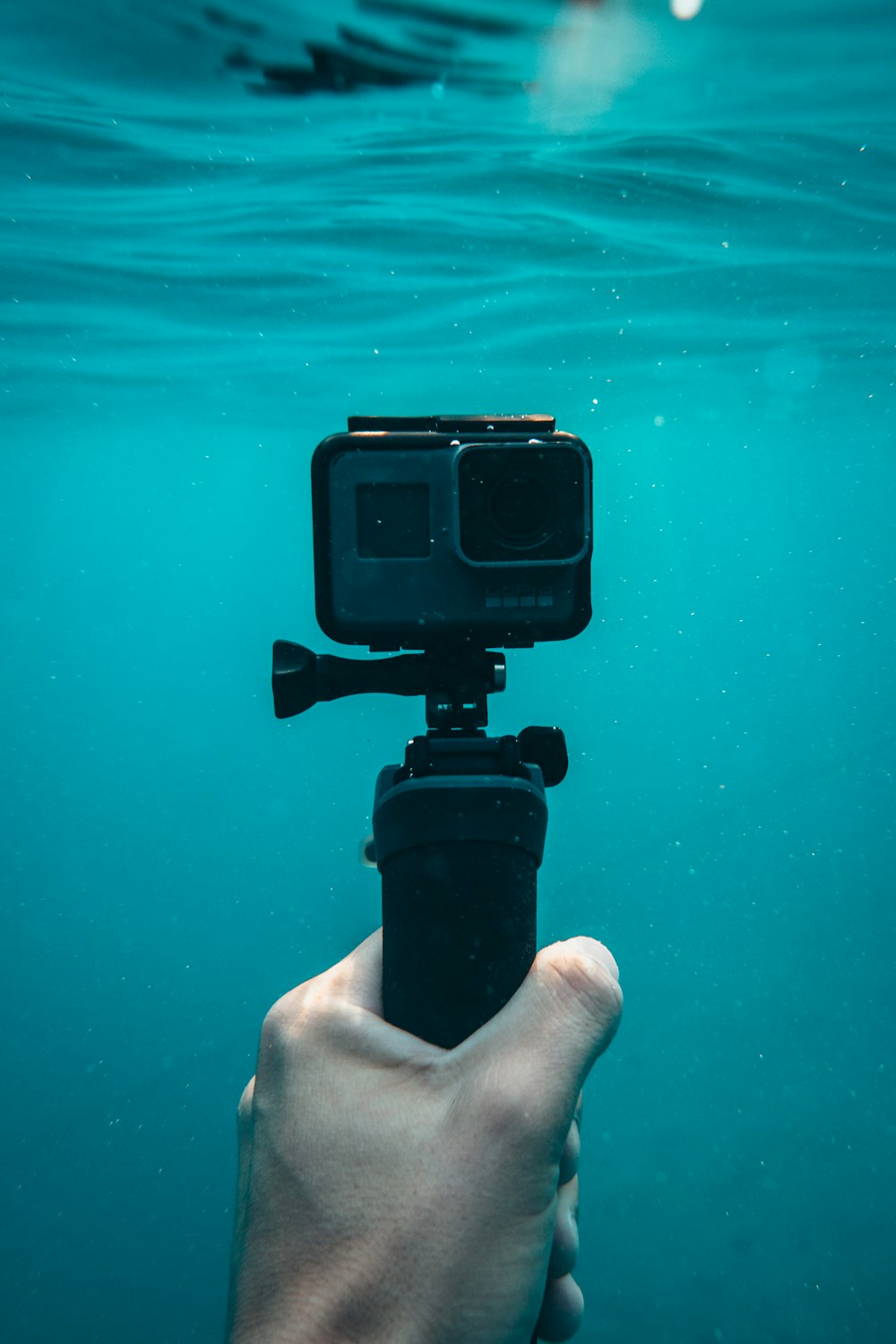pessoa segurando câmera de ação em debaixo d'água