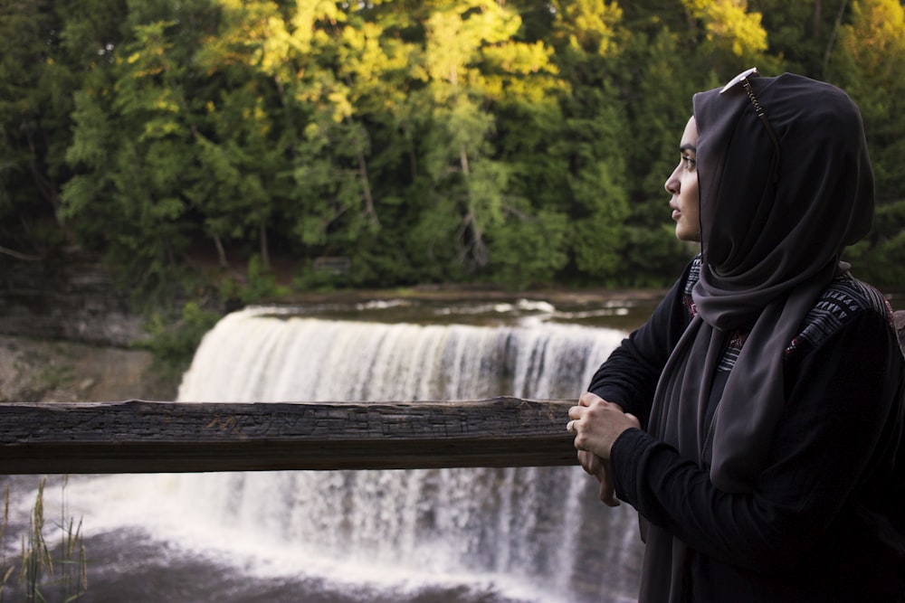 mulher apoiada em grades perto de cachoeiras