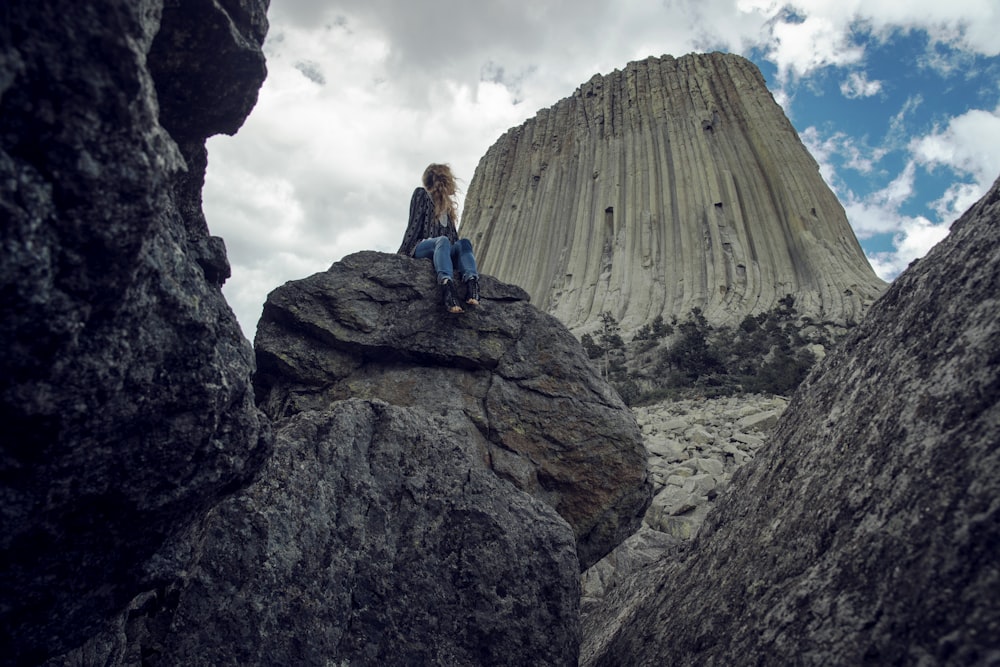 woman seating on rock under blue sky