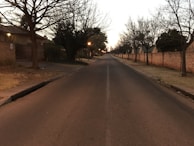 Evening shot of a quiet locality street lined with orange and white boundary walls.