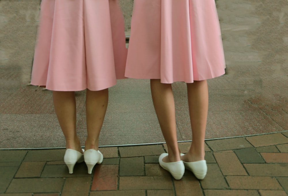 two women wearing pink skirts