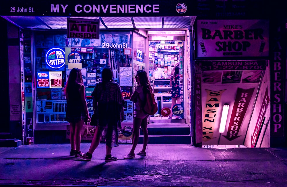 tres mujeres de pie en el escaparate de la tienda de conveniencia
