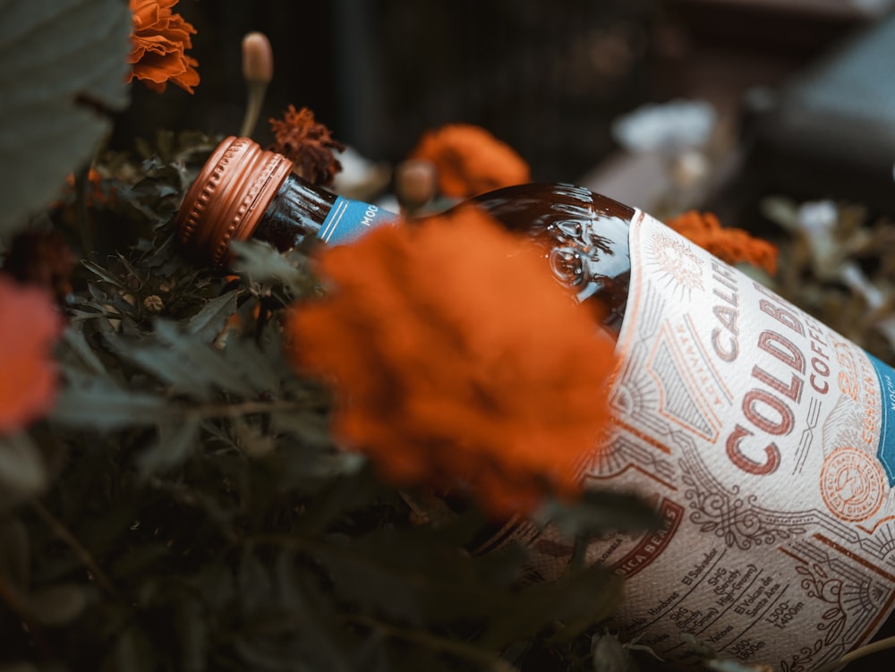 brown glass bottle on orange flower bush