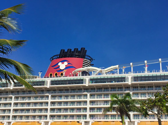 A joyful family waving from the deck of a cruise ship under a bright blue sky.